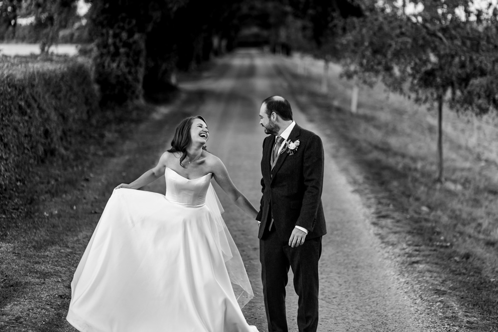 bride and groom laughing while holding hands 